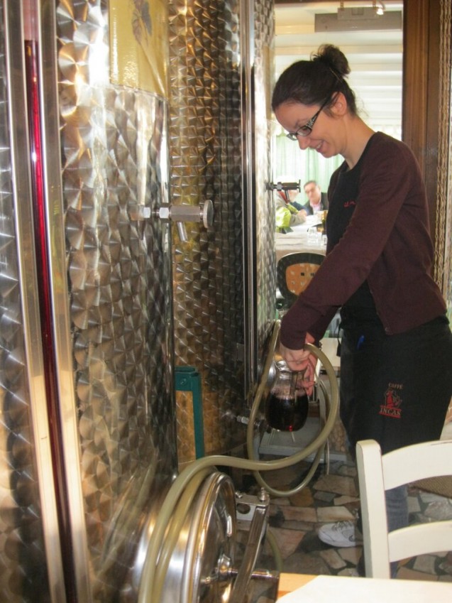 Server, Silvia, fills up wine pitchers with the hose